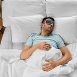 man in eye mask sleeping in bed at home Bezdech senny – przyczyny, objawy i leczenie